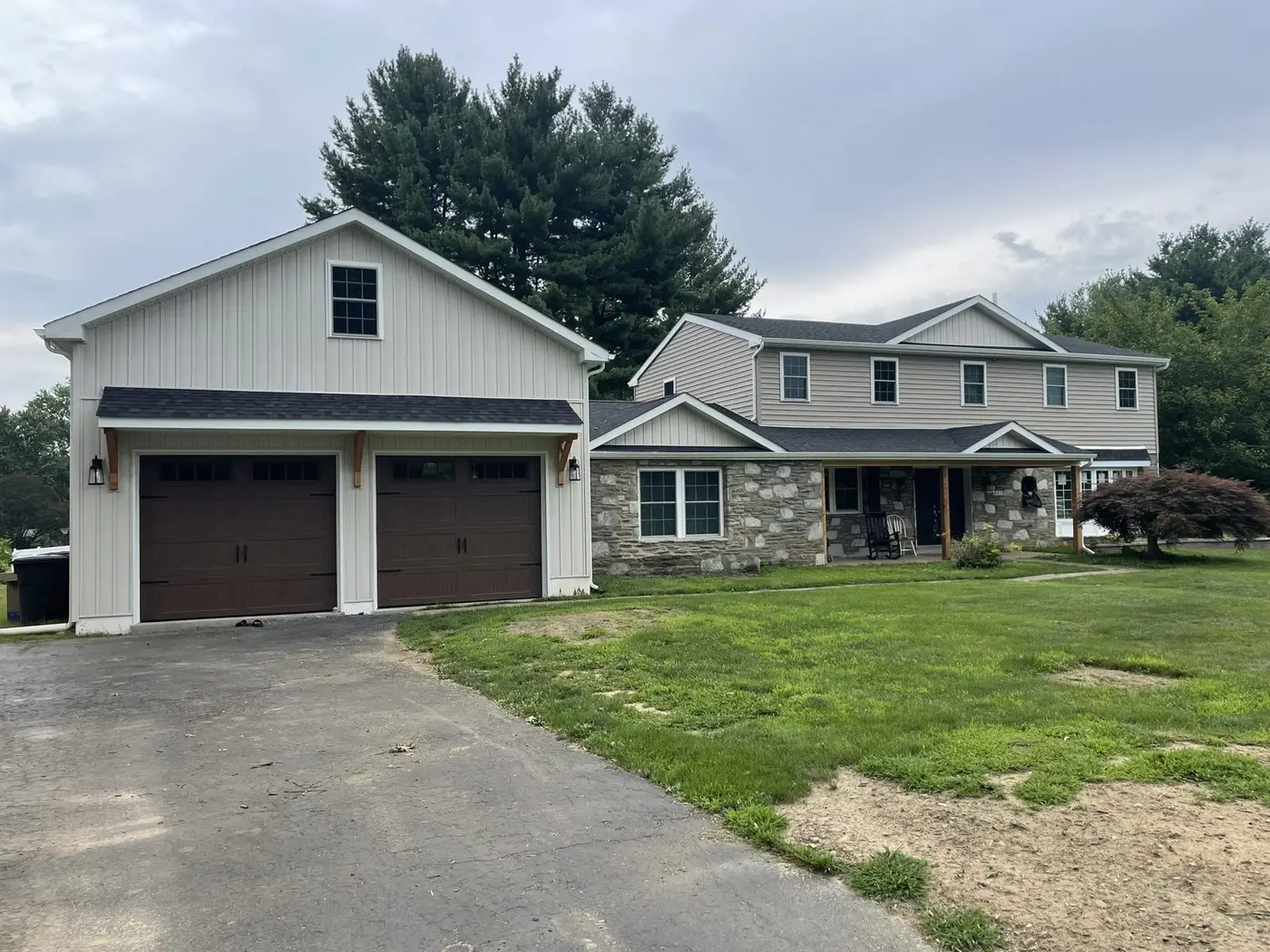Finished addition in Huntingdon Valley, PA: a new two-car garage with brown doors beside the stone-fronted house