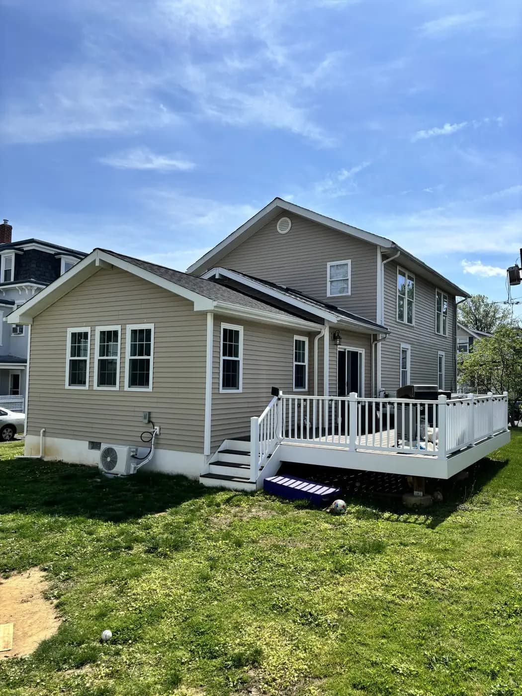 Finished rear addition with siding, deck, and steps down to the lawn