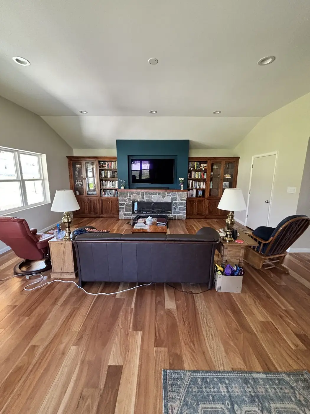 Family room with maple built-ins on both sides of the stone fireplace, a TV above, and hardwood floors