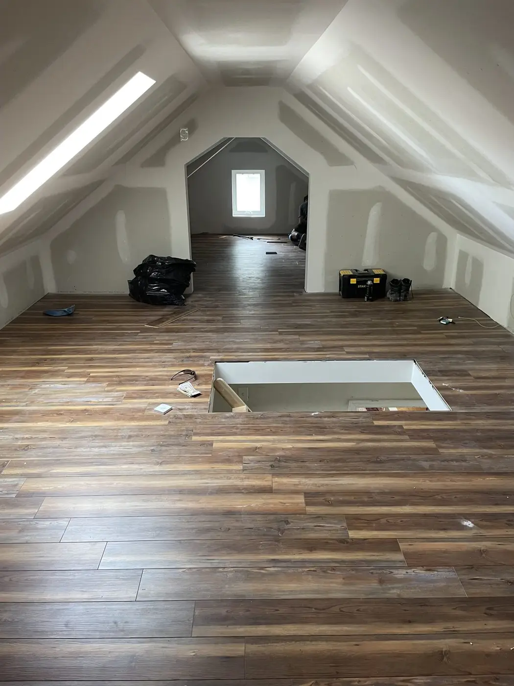 Finished attic sitting room with new wood flooring, a sloped ceiling, and a window at the gable end